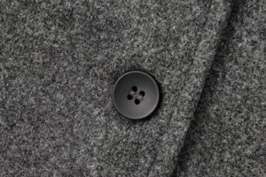 Vue rapprochée détaillée de la texture du tissu du manteau et du design des boutons.