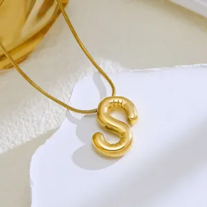 Close-up detailopname van een vergulde halsketting met een glanzende letter S hanger.