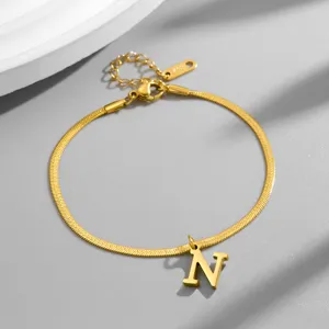 Close-up detail of the gold snake chain bracelet featuring an elegant letter N pendant.