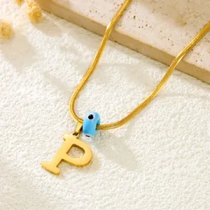 Gold snake chain necklace with letter P pendant and blue evil eye bead detail view fashion.