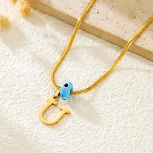 Gold snake chain necklace featuring letter U pendant and blue evil eye bead detail.
