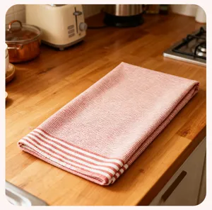 Detail van een rood-wit gestreepte keukedoek, opgevouwen katoenen doek op houten aanrechtblad geplaatst.