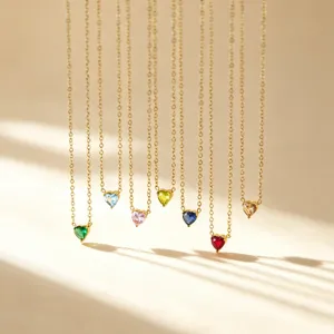 Primo piano dettaglio di eleganti collane con ciondolo pietra natale a cuore dorate.
