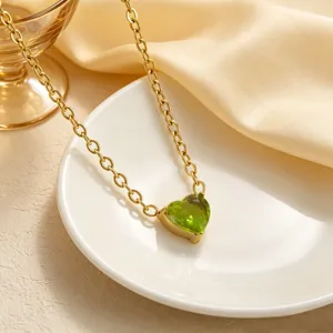 Dettaglio ravvicinato di una delicata collana d'oro con pendente in zircone a cuore verde.