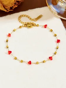 Bracciale a catena dorata con cristalli rossi e quadrati metallici, accessorio di gioielleria chic.