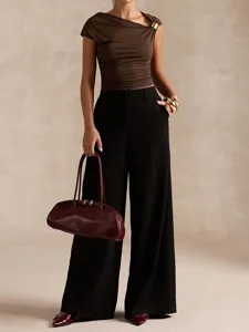 Women asymmetric one shoulder crop top with black wide leg pants and burgundy handbag detail.