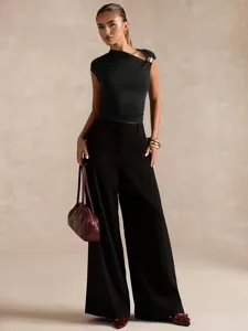 Detailed view of the sleek black asymmetric one-shoulder cropped top paired with trousers.