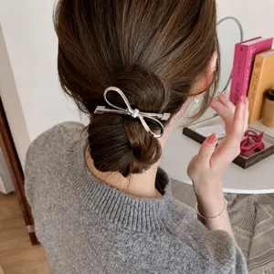 Dettaglio elastico per capelli con fiocco argento, elegante fermaglio in metallo per code o chignon.