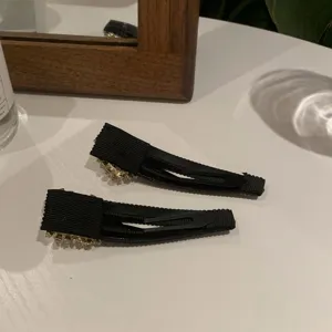 Gros plan détaillé de deux pinces à cheveux en tissu noir avec de superbes strass.