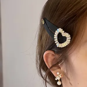 Vue détaillée de la pince à cheveux noire en ruban avec cœur en strass et boucles.