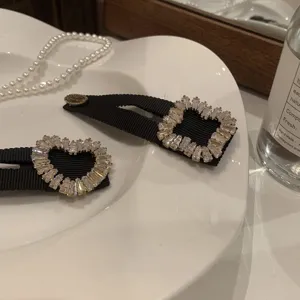 Gros plan sur des pinces à cheveux en ruban noir ornées de strass et cristaux étincelants.