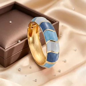 Close-up detail of vintage zinc alloy open bangle featuring blue enamel wave color-blocking and gold trim.
