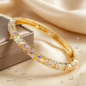 Bracelet jonc doré articulé orné de fleurs en émail violet et de cristaux scintillants pour femmes.