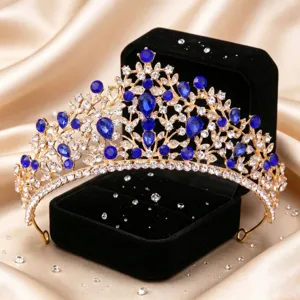 Close-up detail shot of a sparkling blue rhinestone baroque gold bridal tiara on velvet box.