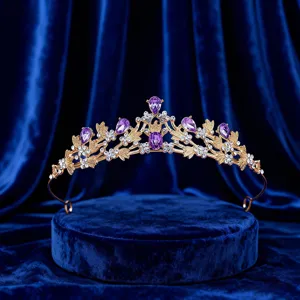 Close-up detail of a golden tiara with sparkling purple teardrop crystals and clear rhinestones.