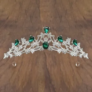 Detailed view of the silver tiara featuring green crystal stones and clear rhinestones.