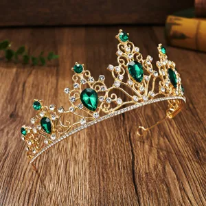 Close-up detail of luxurious gold tiara featuring emerald green crystals and sparkling rhinestones.
