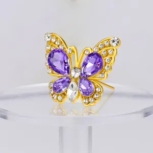 Vista detallada del broche de mariposa con pedrería brillante morada y transparente en aleación.