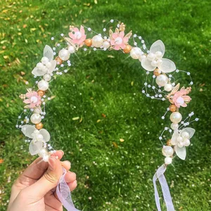 Delicate pink floral hair wreath detail, featuring pearls and ribbons for girls' parties and events.