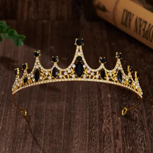 Gold crown tiara detail featuring black and clear rhinestones on dark wood background.