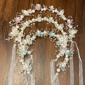 Detailed shot of fairy style floral hair wreath with pearls and ribbons for girls party.