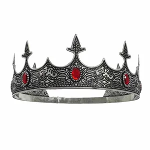 Close-up of retro silver king crown with red gems, detailed metal carving for party costume.