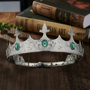 Detailed shot of a vintage silver king crown with green gems, luxury party costume prop.
