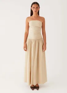 Full-length front view of a beige strapless maxi dress with elegant ruched detailing