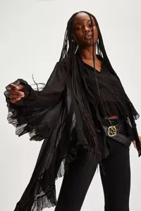Detail of a black sheer blouse with oversized ruffled sleeves and irregular hemline.