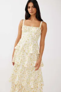 Detail of a white tiered maxi dress with yellow floral print and square neckline.