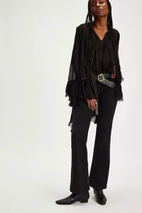 Full body shot of a woman in a black irregular ruffled chiffon shirt and flared jeans