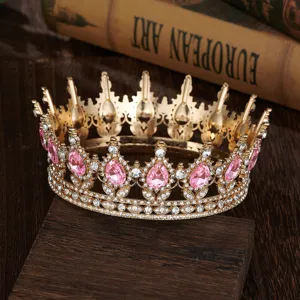 Detailed closeup of a baroque gold crown with pink teardrop rhinestones and crystals.