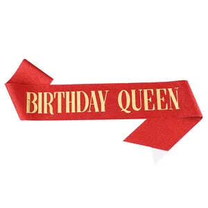 Red glitter birthday queen sash detail, gold metallic text, party celebration prop accessory.