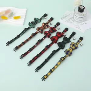 Variety of plaid pet collars with bow ties and bells shown on a mint green background.