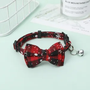 Close-up of red and black plaid pet collar featuring snowflake bow and silver bell.