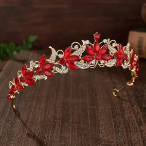 Close-up detail of baroque bridal gold tiara sparkling with red crystals and clear rhinestones.