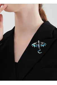 Detailopname van de prachtige donkerblauwe geëmailleerde drakenbroche op zwarte jas.