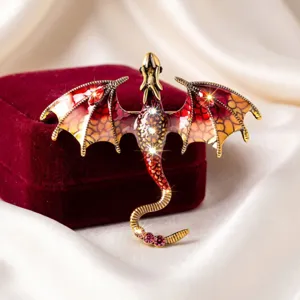 Close-up van vintage drakenbroche met geëmailleerde rode vleugels en fonkelende strasssteentjes.