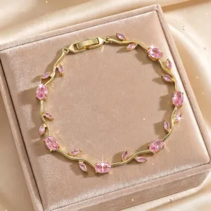 Detail view of a luxury gold-plated vine bracelet featuring sparkling pink cubic zirconia stones.