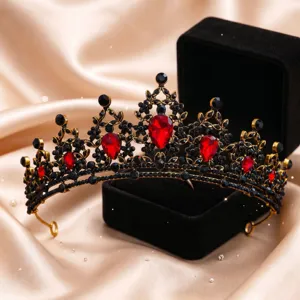 Primo piano dettaglio della tiara di cristallo nero e oro vintage con pietre rosse brillanti.