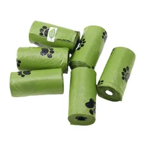 Green dog poop waste bags rolls with cute black paw prints for pet waste cleaning supply.