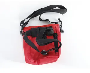 Pet training bag detail showing durable red fabric, black straps, zipper pocket, and dispenser.