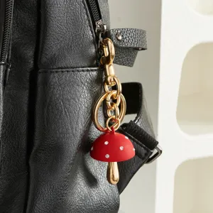 Detailopname van een schattige rode strass paddenstoel sleutelhanger aan leren tas.