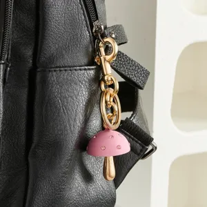 Leuke roze paddestoel sleutelhanger met gouden hardware detail, stijlvolle tasbedel.