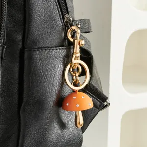 Gedetailleerde close-up van een schattige oranje paddenstoel sleutelhanger aan tas.