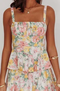 Close-up of floral cami dress with ruffled waist and pink yellow flower pattern.