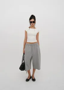 Full body view of grey drawstring wide-leg cropped pants worn by a model in white studio