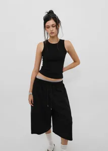 Full body shot of black American vintage style drawstring wide-leg cropped pants on model.