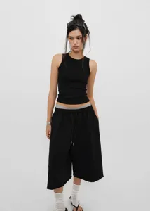 Full view of black vintage loose-fitting wide-leg drawstring culottes paired with a ribbed tank top