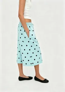 Close-up detail of light blue wide-leg cropped pants with black polka dot pattern.